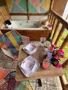 a table with plates and flowers next to a bath tub at RIYA Tesoro de la Montaña Cabaña Haly in Ibagué