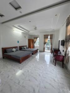 a large bedroom with two beds and a living room at Nhà Nghỉ Hoàng Gia Phát in Buôn Kô Sir