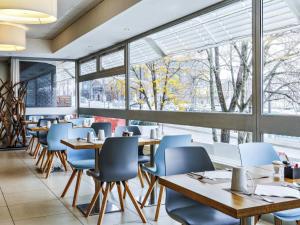 a restaurant with wooden tables and chairs and windows at Mercure Paris Vaugirard Porte De Versailles in Paris