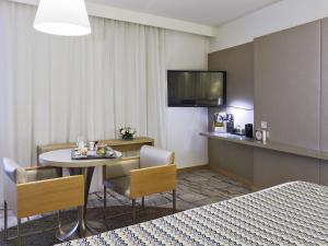 a hotel room with a table and chairs and a television at Mercure Paris Vaugirard Porte De Versailles in Paris