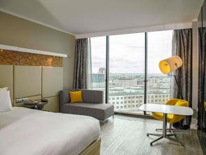 ein Hotelzimmer mit Bett, Stuhl und Fenster in der Unterkunft Pullman Abidjan in Abidjan