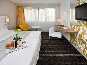 ブール・ガン・ブレスにあるMercure Bourg En Bresseのベッドと机があるホテルの部屋