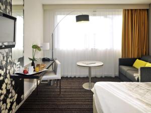 a hotel room with a bed and a couch and a table at Mercure Bourg En Bresse in Bourg-en-Bresse +82 photos