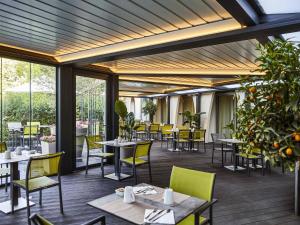 a restaurant with tables and chairs and windows at Mercure Beaune Centre in Beaune
