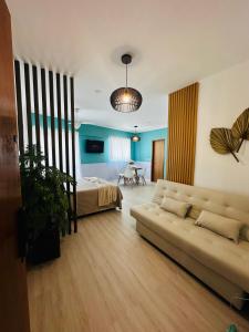 una sala de estar con un sofá y una cama en Studio Aconchego Praia Grande, en Praia Grande