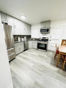 a kitchen with white cabinets and stainless steel appliances at Spacious 4Bdrs house with parking in Hempstead