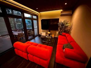 un sofá rojo sentado en una sala de estar en 富士山を見ながらサウナBBQ The No10 MtFuji Forest House, en Yamanakako