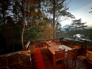 una mesa de madera y sillas en una terraza con árboles en 富士山を見ながらサウナBBQ The No10 MtFuji Forest House, en Yamanakako