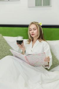 une femme assise dans son lit, tenant un verre de vin dans l'établissement Atermis Regency Hillside Phu Quoc - Sea & Fireworks view- Gym & Pool Access, à Duong Dong