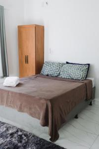 ゴベルナドール・バラダレスにあるApartamento com piscinaの茶色の毛布と木製のキャビネットが備わったベッド