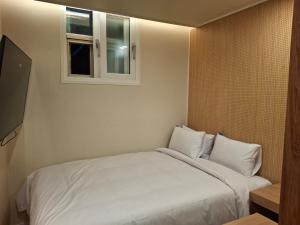 a bedroom with a white bed with a window at Rio Hotel-Hoegi Station, Subway Line 1 in Seoul
