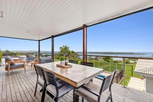 a patio with a table and chairs on a deck at Headland Beauty. in Urunga
