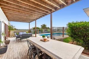 a patio with a table and chairs and a pool at Headland Beauty. in Urunga