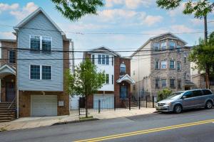 Un coche plateado aparcado delante de unas casas en una calle. en Newark Gem 6BR, 5BA - Sleeps 24 - Walk to Prudential Center and Newark Penn Station, Near EWR and American Dream Mall, includes Parking - WiFi - Laundry - Backyard - Gym, en Newark
