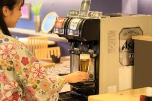 a woman is making a drink in a coffee machine at Yutorelo Echigoyuzawa in Yuzawa
