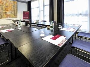 a conference room with tables and chairs and a large window at Mercure Rouen Val de Reuil in Val de Reuil