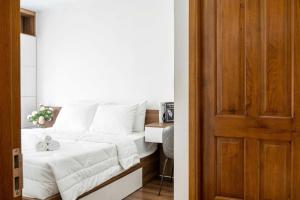 1 dormitorio con cama con sábanas blancas y puerta de madera en The Glory Midori Park VSIP, en Ga Phú Trung