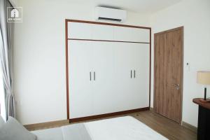Un dormitorio con un armario blanco con un televisor encima. en The Glory Midori Park VSIP, en Ga Phú Trung 2 fotos más