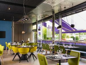 a restaurant with tables and yellow chairs at Mercure Mulhouse Centre in Mulhouse