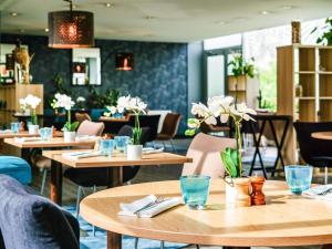 Un restaurante con mesas, sillas y flores. en Mercure Paris Orly Rungis Aéroport, en Rungis