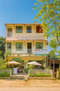 un edificio amarillo con sombrillas delante en HCA Homestay, en Ha Giang