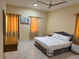 Un dormitorio con una cama y una mesa y una ventana. en هومي Homi, en Salalah