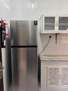 ein Edelstahlkühlschrank in einer Küche mit weißen Schränken in der Unterkunft أجاويد لشقق المفروشة 1 Ajaweed Residence in Salalah