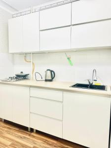 a white kitchen with white cabinets and a sink at City Apartments in Uralsk