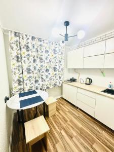 a kitchen with white cabinets and a table at City Apartments in Uralsk