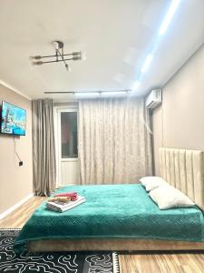 a bedroom with a green bed and a window at City Apartments in Uralsk +2 photos