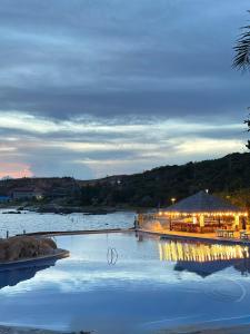a restaurant with lights on the water at dusk at Rock Water Bay Beach Resort & Spa in Xóm Tram +11 photos