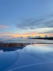 a pool of water with a sunset in the ocean at Rock Water Bay Beach Resort & Spa in Xóm Tram