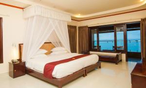 a bedroom with a canopy bed with a view of the ocean at Rock Water Bay Beach Resort & Spa in Xóm Tram