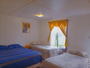 a room with two beds and a window at Cabañas Kravainn in Hanga Roa
