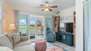 a living room with a couch and a flat screen tv at Coral Breeze by AvantStay Close to Beach w Balcony Shared Pool Month Long Stays Only in Stock Island
