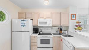 Coral Breeze by AvantStay Close to Beach w Balcony Shared Pool Month Long Stays Only في ستوك آيلاند: مطبخ مع ادوات بيضاء وثلاجة بيضاء