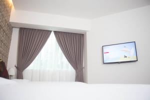 a bedroom with a white wall and a blue curtain at Qlassic Hotel in Sepang
