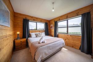 a bedroom with a bed and a large window at The Back Hut - Te Anau Holiday Home in Te Anau