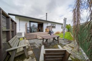a patio with a wooden table and a bench at The Back Hut - Te Anau Holiday Home in Te Anau