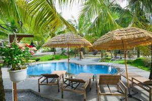 a resort with tables and umbrellas and a pool at Biển Tôm ốc Homestay Bến Tre - Hồ Bơi & BBQ Garden in Ấp Sơn Thuận (2)