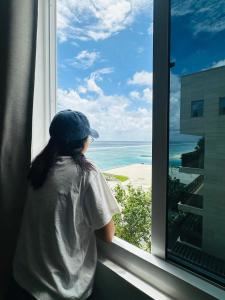 a little girl looking out a window at the beach at Nala Host- Sea Breeze 1BR apartment in Hulhumale