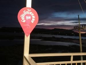 a red sign on a pole in front of a fence at ชมวิว บึงโขงหลง in Ban Don Klang