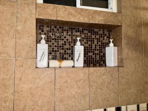 three soap bottles on a shelf in a bathroom at Casa Futuro in San Lorenzo +47 photos