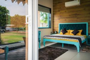 a bedroom with a blue bed with yellow pillows at Hidden Gem near Jaipur horse ride, scenic view & swimming pool in Pachār