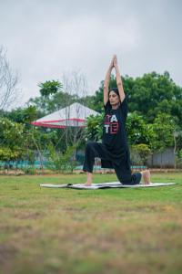 a man doing a yoga pose in the grass at Hidden Gem near Jaipur horse ride, scenic view & swimming pool in Pachār