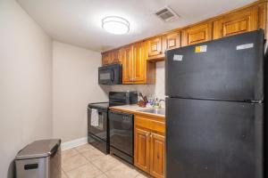 a kitchen with a black refrigerator and wooden cabinets at Landing Spectacular 1BD Pool Gym in West Baton Rouge