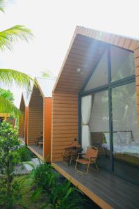 ein Haus mit einer Holzterrasse mit einem Bett in der Unterkunft Biển Tôm ốc Homestay Bến Tre - Hồ Bơi & BBQ Garden 