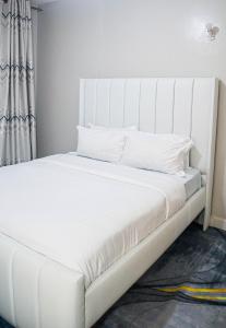 a white bed with a white headboard in a room at Parklands Modern 1-Bedroom Apartment near Aga Khan & Diamond Plaza in Nairobi