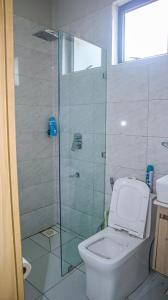 a bathroom with a toilet and a glass shower at Parklands Modern 1-Bedroom Apartment near Aga Khan & Diamond Plaza in Nairobi +8 photos
