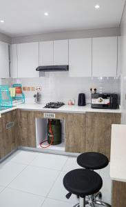 a kitchen with white cabinets and two stools at Parklands Modern 1-Bedroom Apartment near Aga Khan & Diamond Plaza in Nairobi